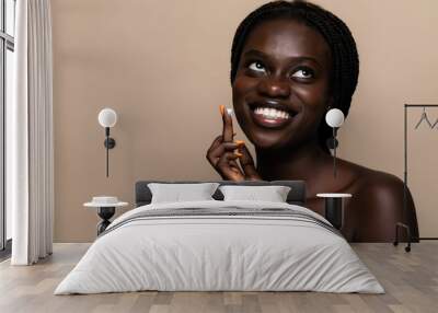 Young african american beauty using face cream isolated on beige background Wall mural